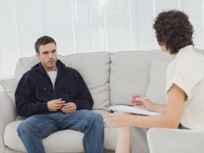 Therapist talking to her patient who is sitting on couch